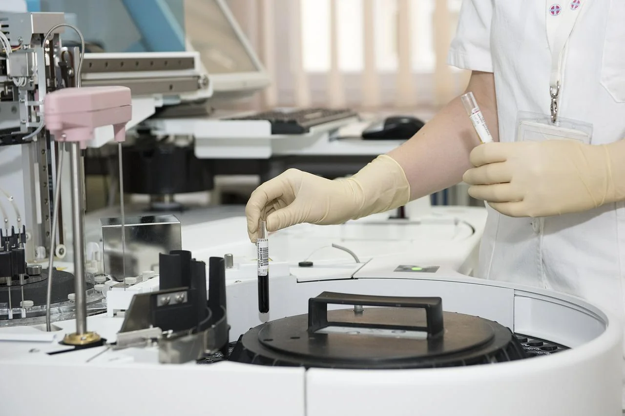 Laboratory technician processing samples on an automated analyser